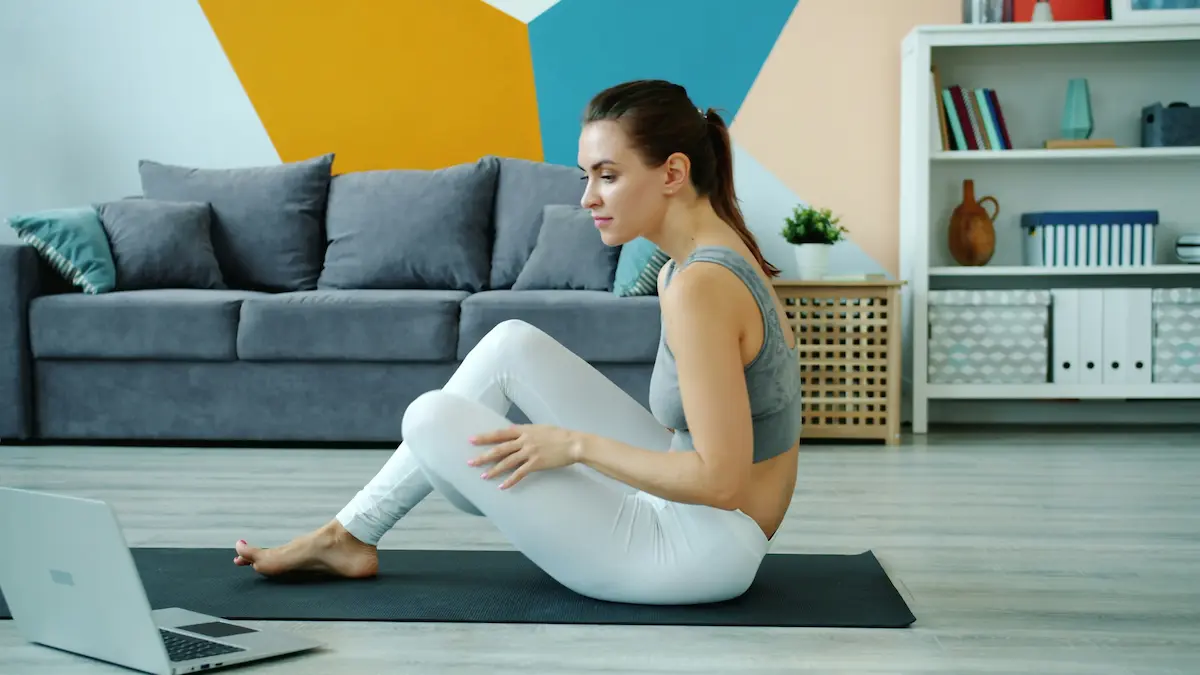 Mulher praticando exercícios e alongamento na sala de casa, buscando desenvolvimento pessoal e bem-estar.