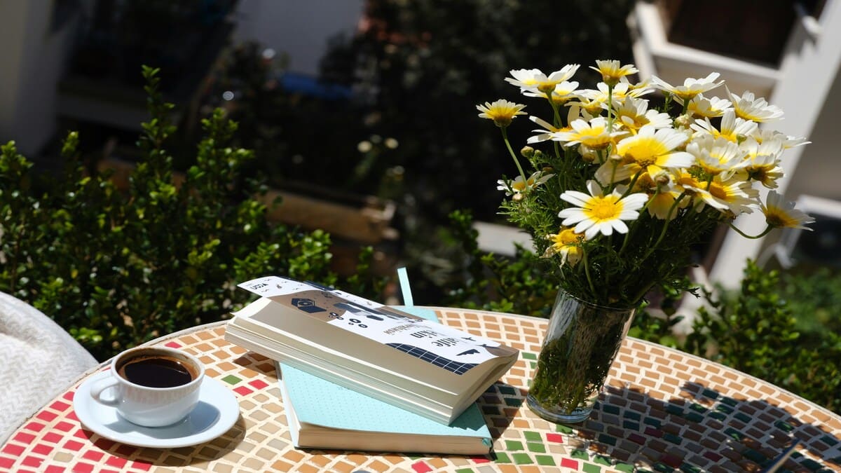 Mesa minimalista de madeira com caderno aberto, xícara de chá, planta pequena e luz suave da manhã, representando planejamento diário e as leis do sucesso.
